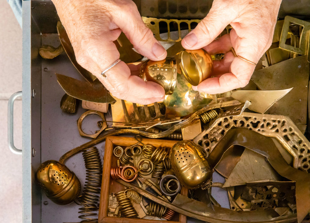 A birds eye view of Sonne's hands above a draw filled with found brass material 