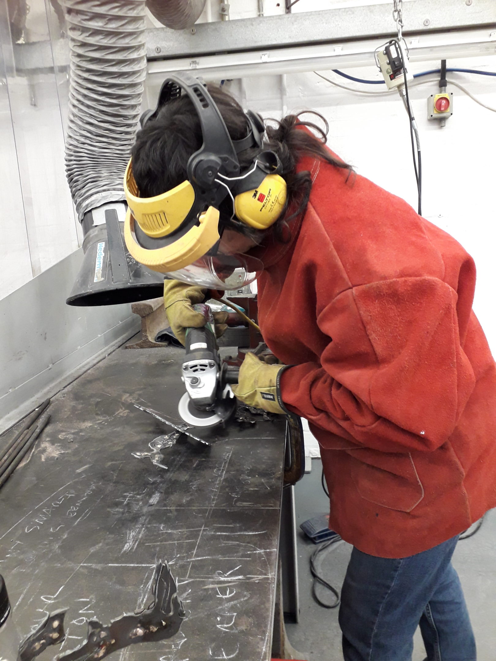 Natasha in an orange boiler suit in the workshop